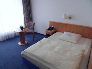 a bedroom with a bed and a table and a chair at Hotel Stadt Homburg - An den Universitätskliniken in Homburg