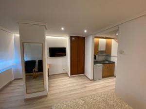 a living room with a mirror and a kitchen at Apartamentos San Fermín in Vitoria-Gasteiz