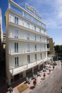 a hotel with chairs and umbrellas in front of it at Hotel Plaza in Gabicce Mare