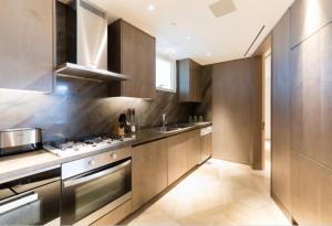 La cuisine est équipée de placards en bois et d'un four avec plaques de cuisson. dans l'établissement Five Palm Residences Dubai - 2BR Fully Furnished, à Dubaï