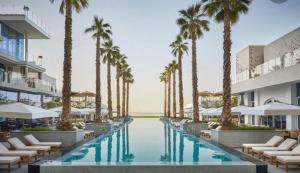 - une piscine avec des palmiers et des chaises longues dans l'établissement Five Palm Residences Dubai - 2BR Fully Furnished, à Dubaï