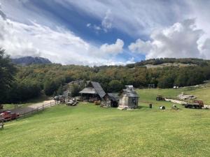 a large green field with a barn in the distance at Etno village Katun in Žabljak