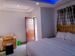um quarto com uma cama, uma cadeira e uma porta em Big Ocean Inn em Ibadan