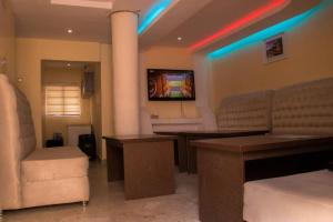 uma sala de espera com uma televisão e uma mesa e cadeiras em Big Ocean Inn em Ibadan