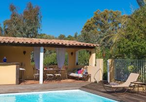 une femme assise sur une terrasse à côté d'une piscine dans l'établissement Villa RUSCANA AVEC PISCINE PRIVÉE, à Sainte-Lucie de Porto-Vecchio