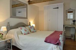 a bedroom with a bed with a mirror on the wall at East Green Farm Cottages - The Old Stables in Saxmundham