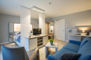 a living room with a blue couch and a tv at Nordsee Lodge in Pellworm