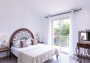une chambre blanche avec un grand lit et une fenêtre dans l'établissement Villa RUSCANA AVEC PISCINE PRIVÉE, à Sainte-Lucie de Porto-Vecchio 11 autres photos