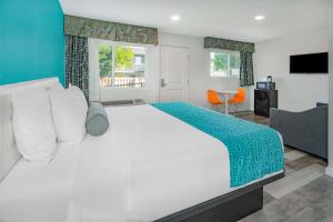 ein Schlafzimmer mit einem großen weißen Bett und einem Tisch in der Unterkunft Howard Johnson Suites by Wyndham San Diego Chula Vista BayFt in Chula Vista