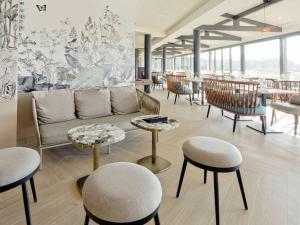 a lobby with a couch and tables and chairs at Mercure Orléans Portes de Sologne in Ardon
