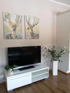a living room with a tv and three deer paintings at ANNA - Modern flat with Sauna - 24h Check in in Närpiö