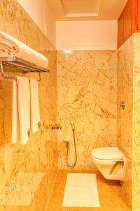 a bathroom with a toilet and a shower with towels at HOTEL ROYAL GRANDE in Vellore +40 photos