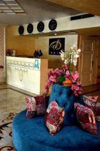 ein Zimmer mit einer blauen Couch mit einer Vase aus Blumen in der Unterkunft Deluxe Hotel Ganja in Ganja