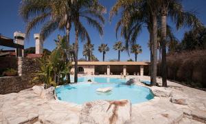 a swimming pool with palm trees and a house at Tenuta Moreno in Mesagne