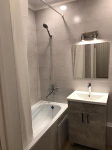 uma casa de banho branca com uma banheira e um lavatório em Стильная однокомнатная квартира в г.Алматы em Almaty