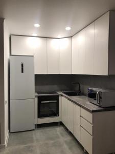 uma cozinha com armários brancos, um lavatório e um frigorífico em Стильная однокомнатная квартира в г.Алматы em Almaty