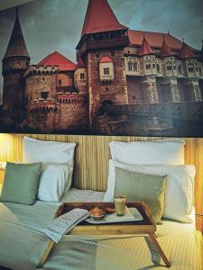 YMY Boutique Residence في بوخارست: سرير عليه صينية عليها لوحة قلعة