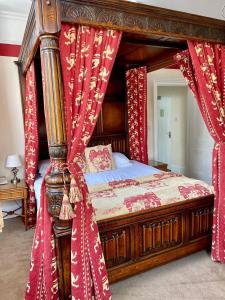 a canopy bed with red drapes in a bedroom at Ebury Hotel Cottages and Apartment's in Canterbury
