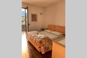 a small bedroom with a bed and a balcony at Acero Rosso in Malonno