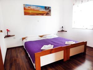 1 dormitorio con 1 cama con edredón morado en Apartment Jadro, en Supetar