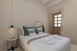 a white bedroom with a large bed with towels on it at Sutor Chic Manor hotel in Rethymno