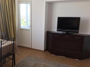 uma sala de estar com televisão numa cómoda com janela em Стильная и уютная однокомнатная квартира в г.Алматы em Almaty