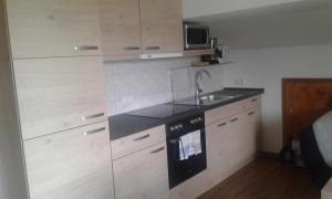 a small kitchen with wooden cabinets and a sink at Haus Guggemos in Hopferau