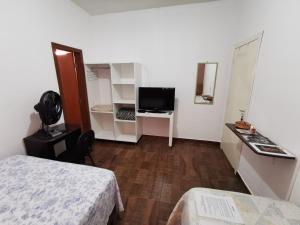 a room with a bed and a desk with a television at Suíte Capitólio in Capitólio