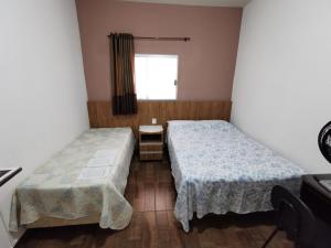 2 camas en una habitación pequeña con ventana en Suíte Capitólio, en Capitólio