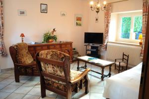 a living room with a desk and chairs and a television at Au Pied du Chateau in Lichtenberg