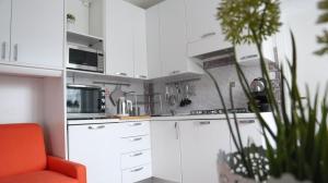 una cocina con armarios blancos y una silla naranja en La Casa di Pamy, en Bellaria-Igea Marina