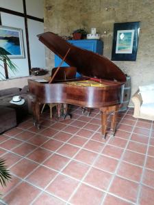 un pianoforte seduto su un pavimento piastrellato in soggiorno di Maison d'Hotes Le Chai d'Armagnac a Monguillem