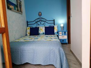 een slaapkamer met een bed met een blauwe muur bij Bilocale Punta Rosa - Fronte Spiaggia in Otranto