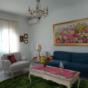 a living room with a blue couch and a table with flowers on it at NN Luxury Apartment near Athens airport in Spata