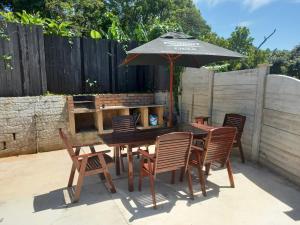 einen Holztisch mit Stühlen und einem Sonnenschirm in der Unterkunft Poolside Guest House in Port Shepstone