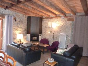 a living room with leather furniture and a stone wall at la grange avec spa in Saint-Aventin