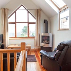 a living room with a leather couch and a fireplace at Mews Cottage Bangor in Bangor