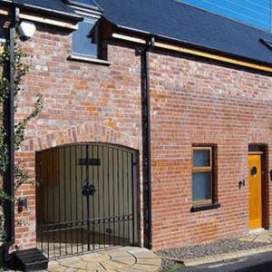 a brick building with a gate on the side of it at Mews Cottage Bangor in Bangor