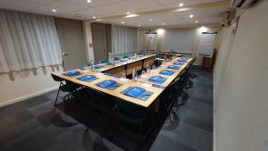 una grande sala conferenze con un lungo tavolo con tovaglioli blu di Campanile Bordeaux Nord - Le Lac a Bordeaux