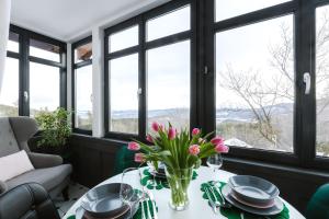 uma mesa com um vaso de flores com janelas em Apartamenty AstoriA em Karpacz