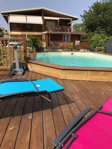 a wooden deck with a swimming pool and yoga mats at VILLA MARINA Appart Hotes in Bouillante