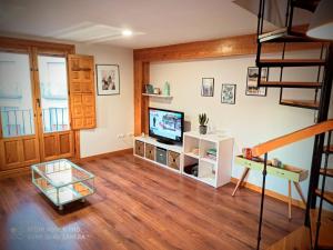 a living room with a television and a staircase at Moneda 46 in Cuenca