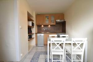 a kitchen with wooden cabinets and white stools at Le Bateau Lavoir in Port-en-Bessin-Huppain