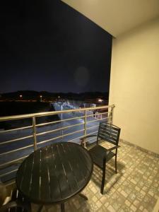 uma mesa e uma cadeira numa varanda à noite em Toot House El Wsam em Taif