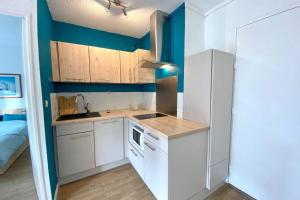 una pequeña cocina con armarios blancos y paredes azules en Logement 4 lits en plein coeur de Cabourg en Cabourg