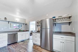 uma cozinha com armários brancos e um frigorífico de aço inoxidável em Cottage on the Canal em Eureka