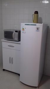 a microwave sitting on top of a white refrigerator at Ótima localização in Águas de Lindóia