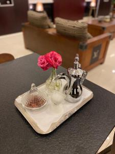 a tray with a vase with a flower and a tea kettle at Toot House El Wsam in Taif