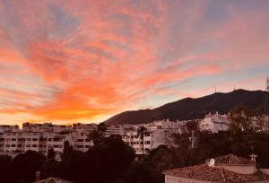 a sunset over a city with buildings and mountains at Exclusive New Apartment in Benalmádena