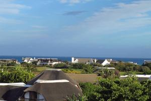 a view of a house with a thatched roof at WitsEnd Almost Heaven in St Francis Bay